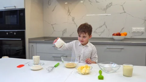 A small boy mixes the egg mass in a clear glass bowl Video stock 128834062