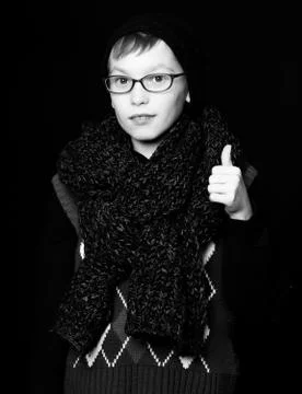 Small boy nerd in glasses on black background, holds thumb up Stock Photos