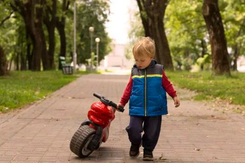 A small boy playing outside with a plastic toy motorbike. Stock Photos