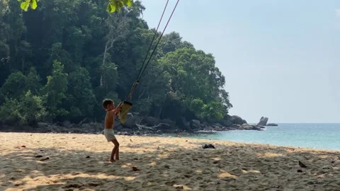Small boy playing with swing at the beautiful beach Stock Footage 277609012