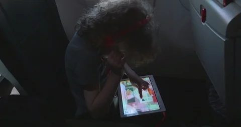 Small boy plays games on his tablet computer on an aeroplane Video stock 107454399