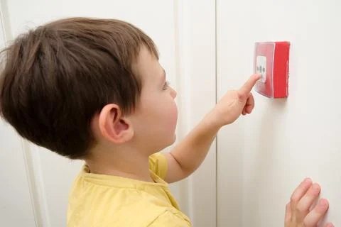 Small boy pushing the fire alarm button, a playful childs curiosity with a .. Stock Photos