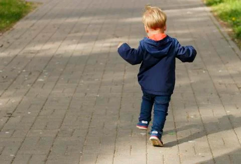Small boy running in the park. Back view of toddler on the walk in the park Stock Photos
