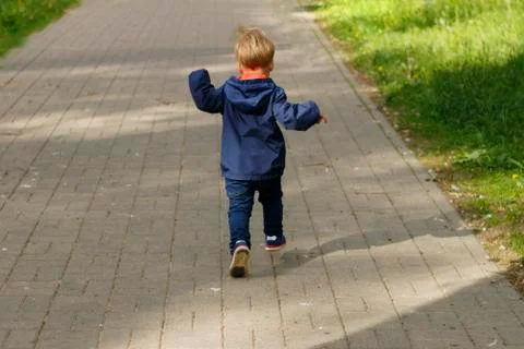 Small boy running in the park. Back view of toddler on the walk in the park. Stock Photos