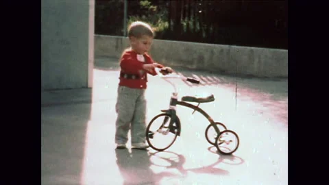 Small boy runs to and pushes tricycle 1960s Stock Footage 172273381