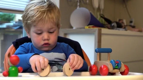 Small boy sits on a highchair with a table and playing with colorful toys Stock Footage 85107985