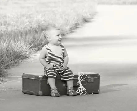 Small boy sits in an old suitcase which tied balloons Stock Photos