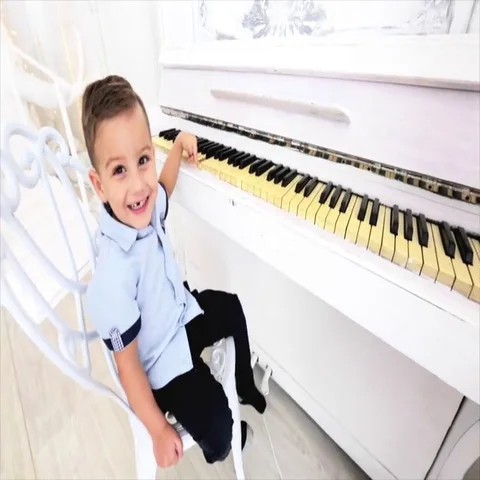 Small boy sits at the piano. boy smiling with his toothless mouth. Stock Footage 69532754