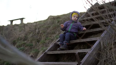 A small boy  sits on wooden steps  Stock Footage 127768809