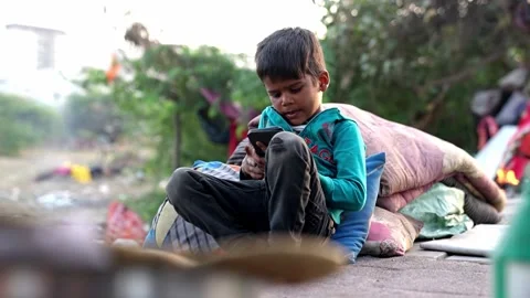 A small boy is sitting on a couch looking at a mobile and playing a game on it Stock Footage 270037998