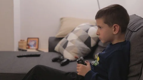 Small boy sitting on couch playing video games Stock Footage 102416109