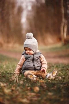 A small boy is sitting on a forest path in a gray jelly Stock Photos