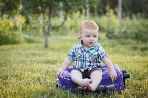 Small boy sitting on an old suitcase Stock Photos