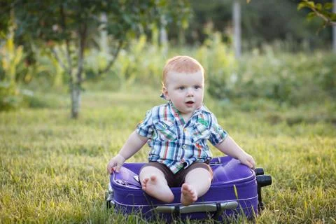 Small boy sitting on an old suitcase Stock Photos