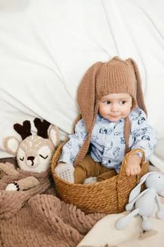 A small boy is sitting in a wicker basket with a hat with rabbit ears Stock Photos
