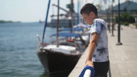Small boy standing and looking at the Dnipro waters in a quay in summer in slo Stock-Footage 113123908