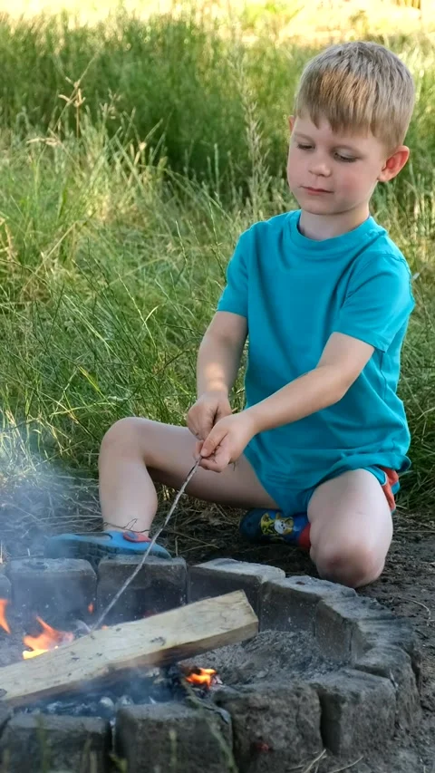 A small boy starts a fire on the ground in a special place in nature. Stock Footage 285707549
