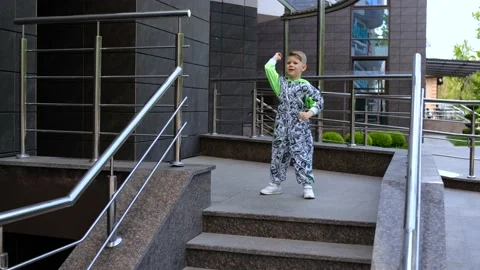 A small boy in a stylish suit dances a HIP-HOP dance near the entrance Video stock 154685879