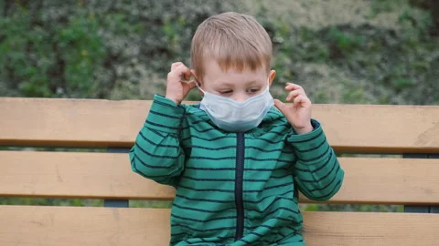 Small boy takes off his face medical mask that protects from coronavirus. Stock Footage 133624558