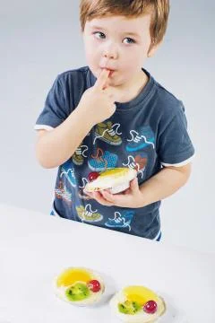 Small boy tasting the fruit cake Stock Photos