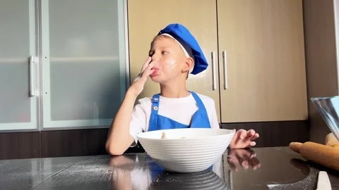 Small boy is tasting raw dough. Son is helping mother to prepare dough Stock Footage 295187858