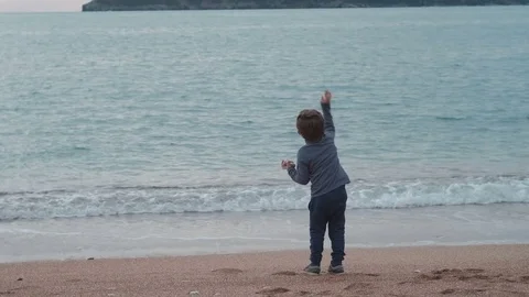 Small boy throw stones to sea. View from back Stock Footage 75253352