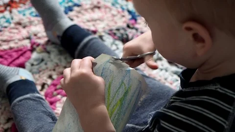 Small boy toddler learns to cut with scissors Stock Footage 93236885