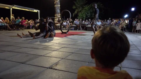Small boy watches performance of black acrobats sitting on the floor 3 Stock Footage 85714086