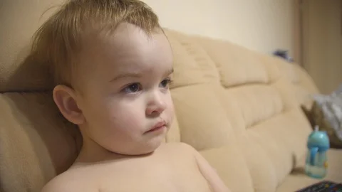 A small boy is watching TV sitting on the sofa Stock Footage 127196066
