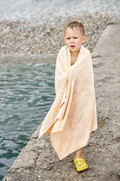 Small boy wrapped with towel gets cold after swimming Stock Photos
