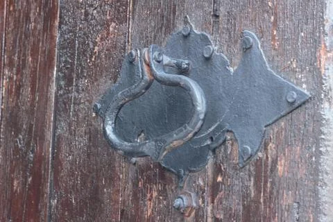 Small brass padlock locking a medieval style wooden gate with iron reinforc.. Stock Photos