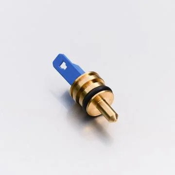 A small brass plumbing valve component with a blue plastic part and a black r Stock Photos