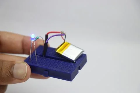 Small breadboard with glowing LED and the lithium polymer battery Stock Photos