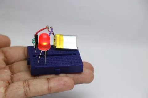 Small breadboard with glowing red LED powered by lithium polymer battery Stock Photos