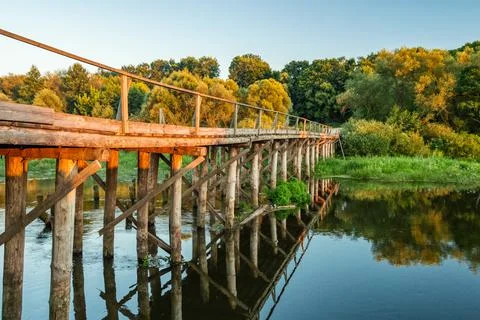 A small bridge over the river in the forest against the background of the sun Stock Photos
