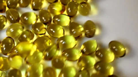 Small bright yellow shiny transparent oval capsules are raked to the sides. Real Stock Footage 145108752