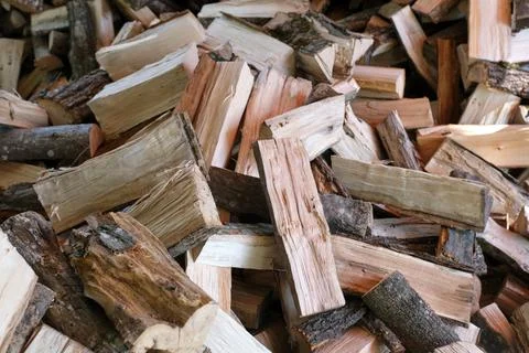 Small brown chopped firewood with grey bark pile lies Foto stock