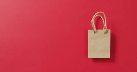 Small brown gift bag with string handles on red background with copy space Stock Footage 342594410