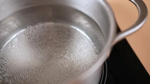 Small bubbles slowly rise from the boiling of the water in the pan. Stock Footage 250322485