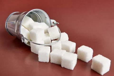 A small bucket with cubes of pressed sugar on a brown background. Foto stock