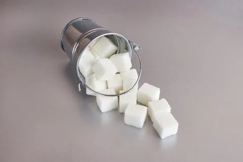 A small bucket with cubes of pressed sugar on a gray background. Stock Photos