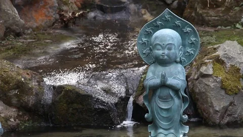 Small Buddhist statue in front of waterfall Stock Footage 104418409