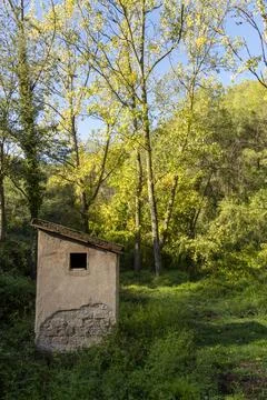A small building with a window sits in a grassy field Stock Photos