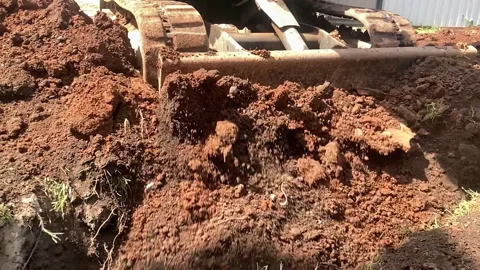 A small Bulldozer pushes soil with a blade, burying a katlavan, slow motion Stock Footage 264786542