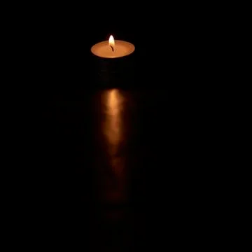 Small burning candle on black background Stock Photos