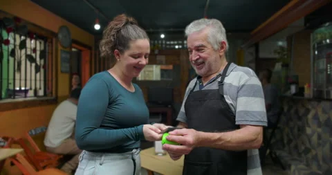Small business café owner processing contactless payment with young woman inside Stockbeeldmateriaal 327386204