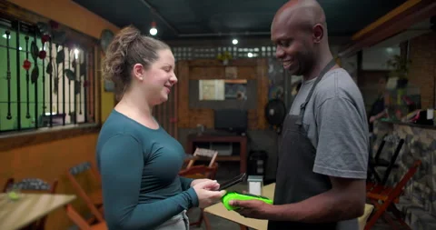 Small business café staff processing contactless payment with young woman inside Stock Footage 327386441
