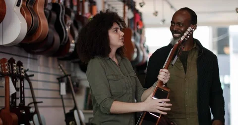 Small business owner helping customer in a guitar store Stock Footage