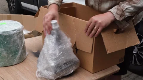 Small Business Owner Reusing Plastic Packaging to Pack Parcel on Table Stock Footage 339755560