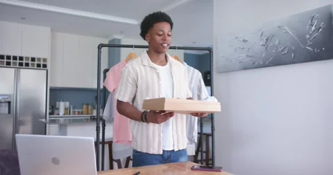 Small business owner standing at kitchen table, waving then opening shoebox Stock Footage 336716349